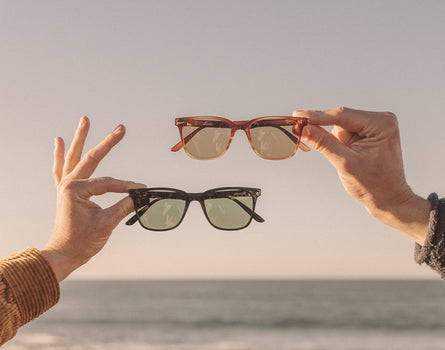2 hands holding 2 pairs of sunski ventana sunglasses