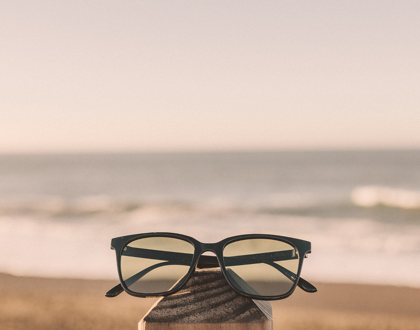 sunski ventana sunglasses on a rail by the beach