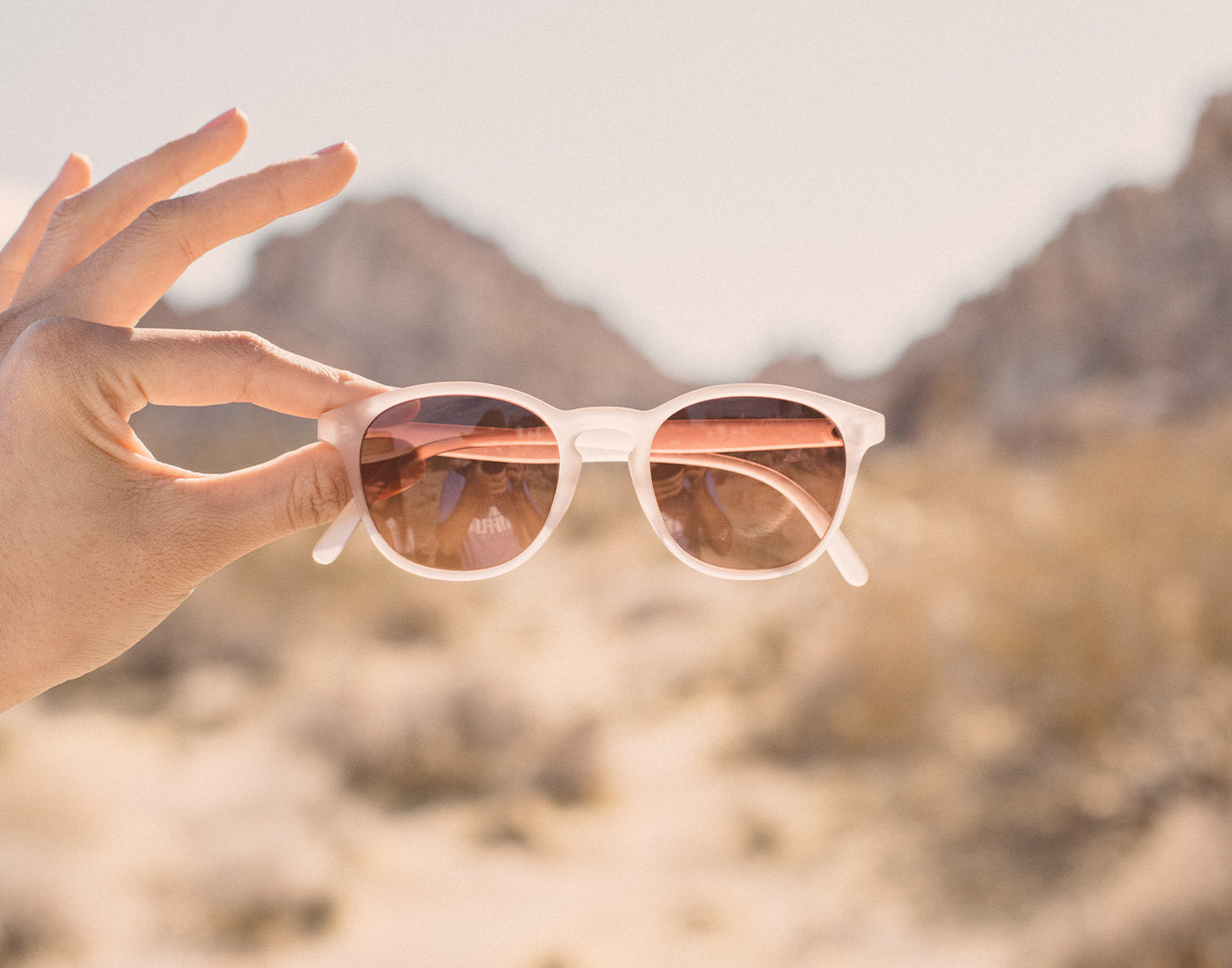 hand holding sunski yuba sunglasses in desert