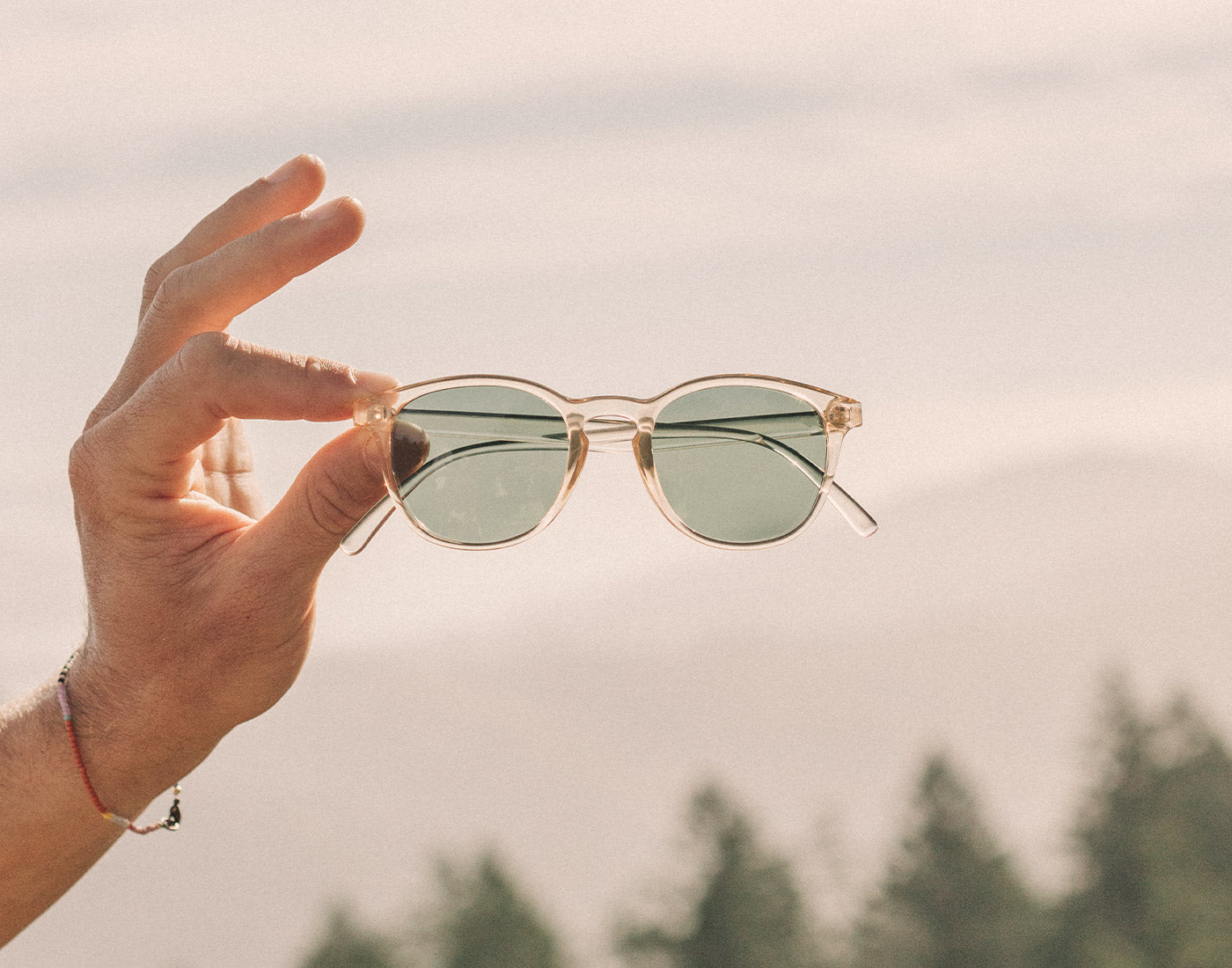hand holding sunski yuba sunglasses in mountains