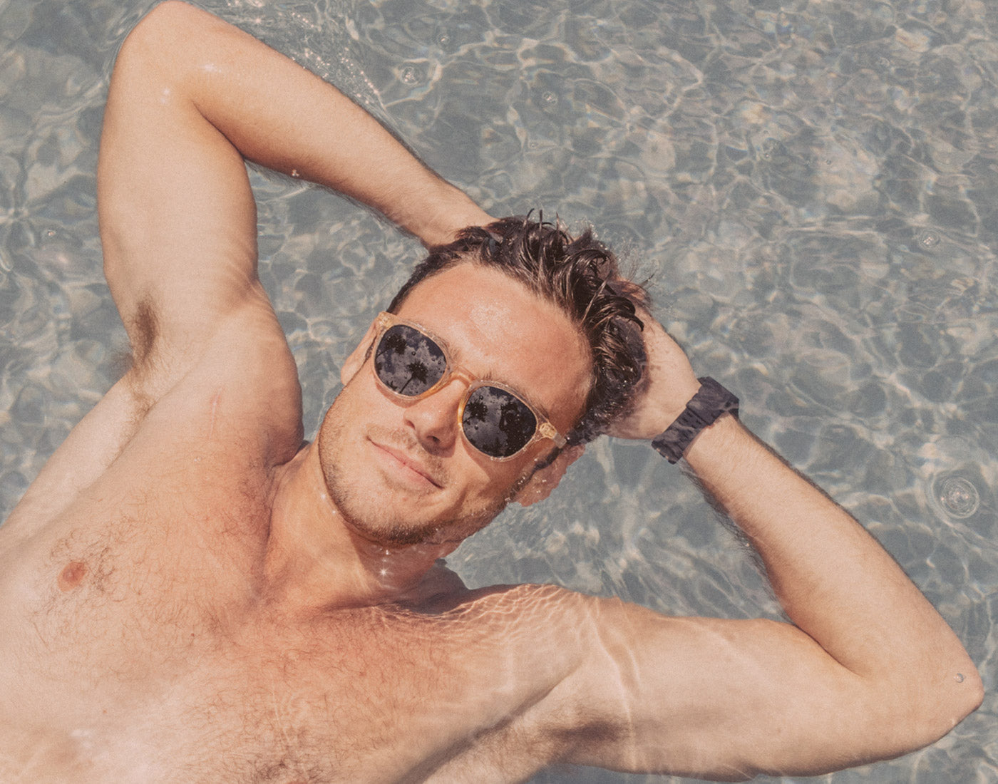 guy floating in pool wearing sunski yuba sunglasses