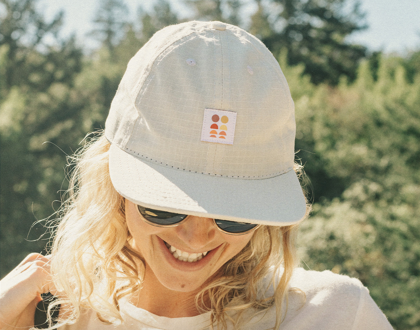 girl looking down laughing wearing sunski sun up hat