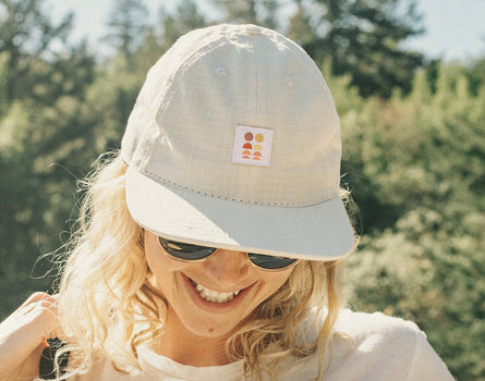 girl looking down laughing wearing sunski sun up hat