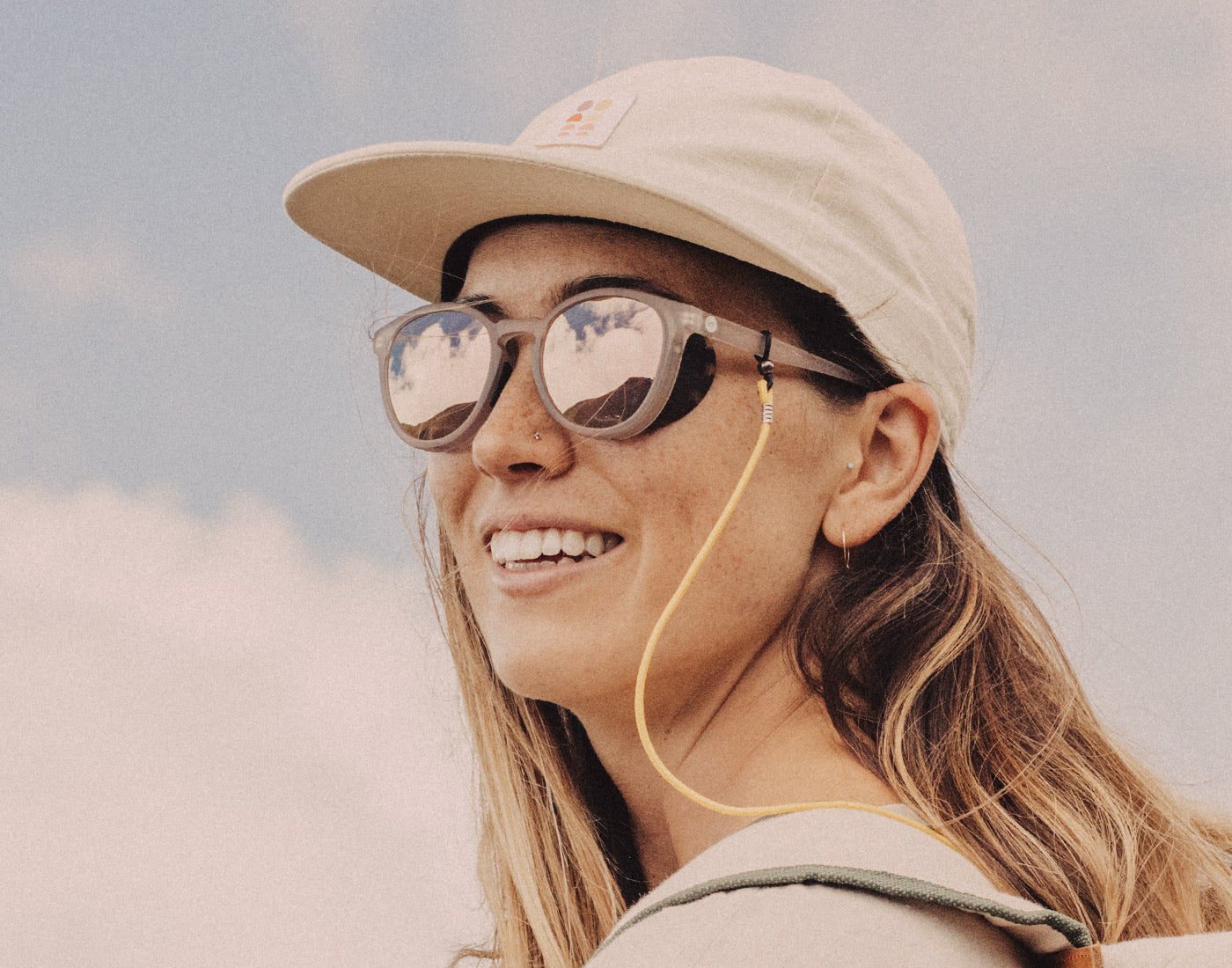 girl in a sunski hat and shades using sunski sunglasses retainer